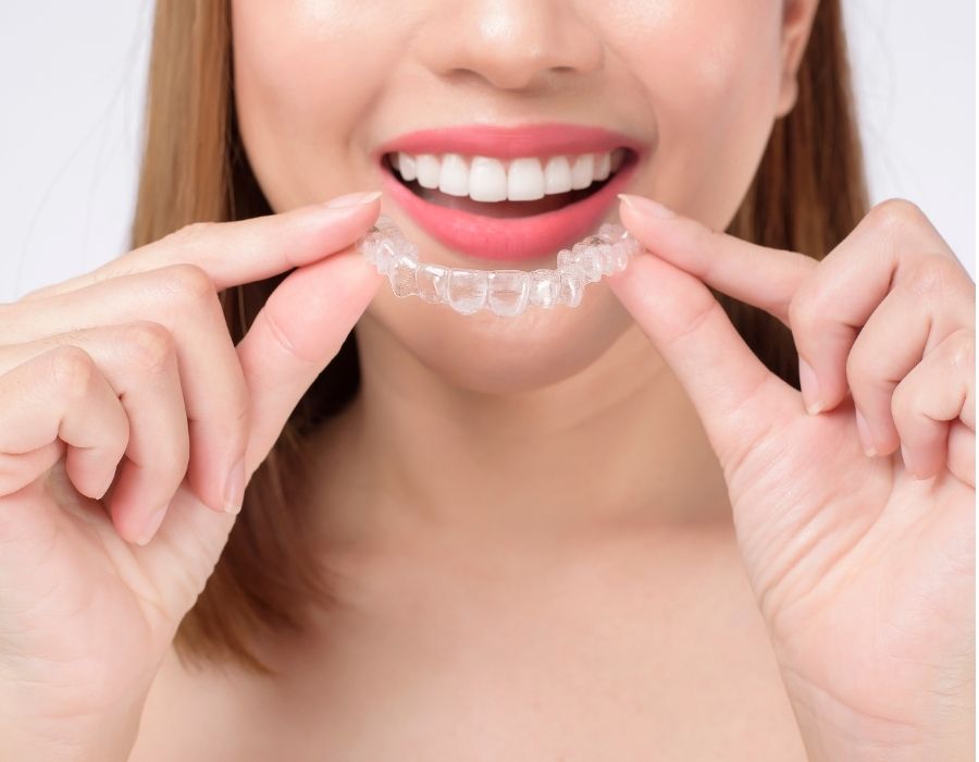Woman holding invisalign for orthodontic teeth straightening
