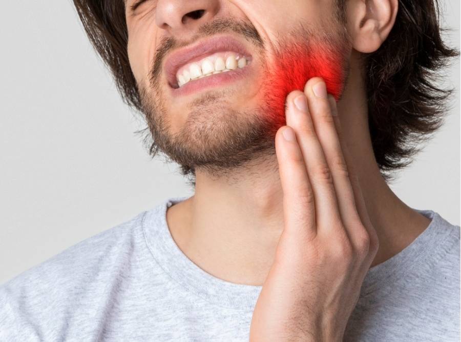 Man with severe toothache holding jaw with red highlighted pain area